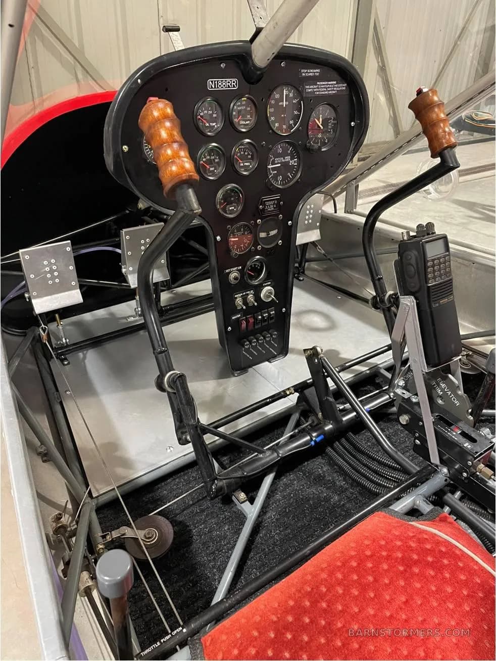 The cockpit of the RANS S-12 Airaile, showing the instrument panel, wooden control sticks, and a handheld radio.