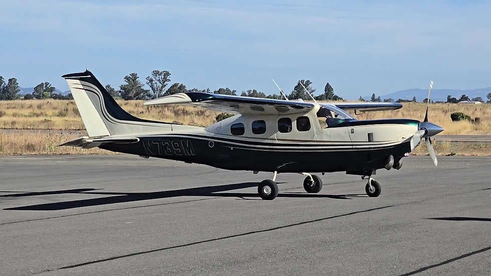 A Cessna 208 Caravan aircraft with a white and green paint scheme is parked on the tarmac.