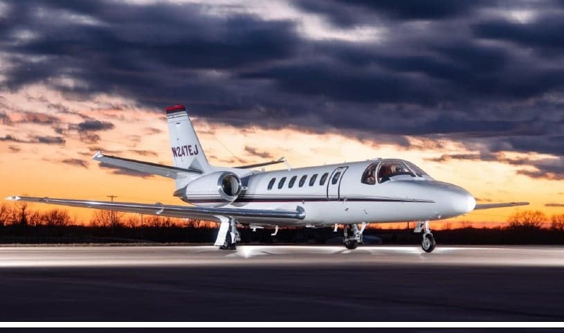 A Cessna Citation CJ3 sits on the tarmac at sunset.