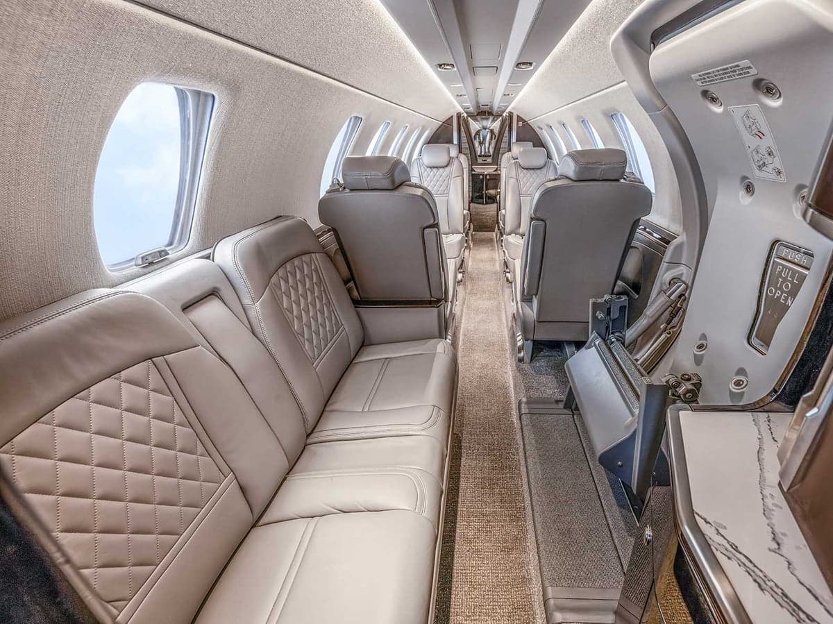 View of the Citation CJ4 cabin featuring gray leather seats and light-colored carpet.