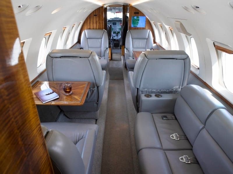 View of the aircraft interior with leather seats and wooden accents.