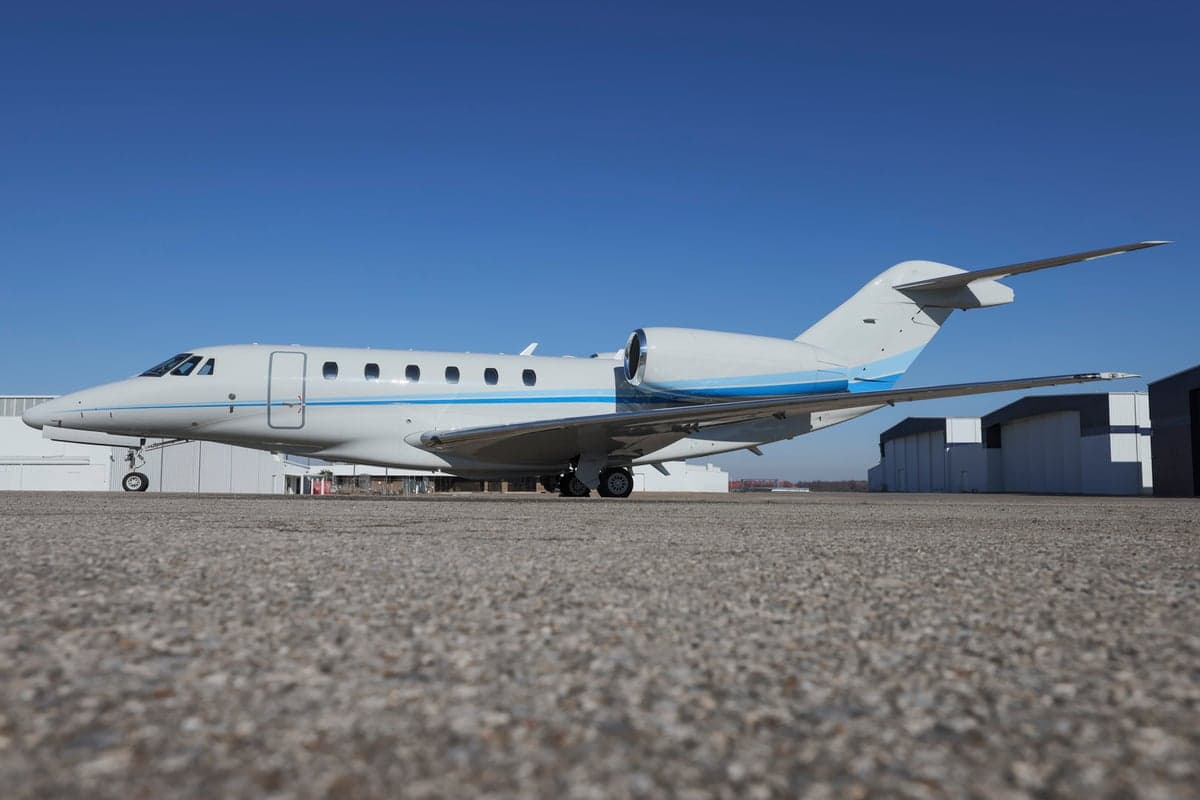 A Citation CJ3 aircraft with a blue and white paint scheme parked on the tarmac.