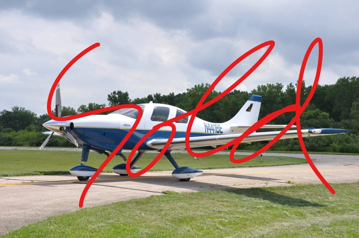 A Cirrus SR22 aircraft with a blue and white paint scheme is parked on the tarmac, with the word 'SOLD' overlaid.