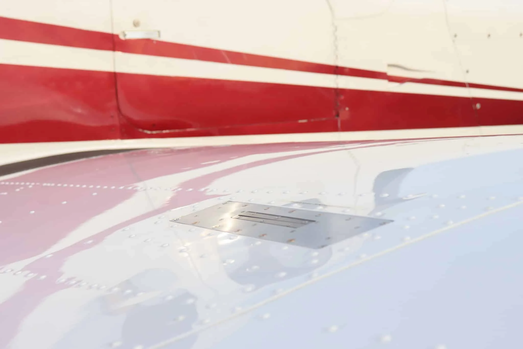 Close-up view of the wing surface and fuselage of the white and red aircraft.