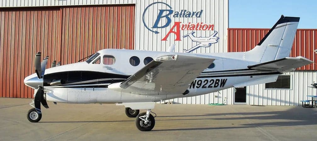A Beechcraft King Air is parked in front of a hangar.