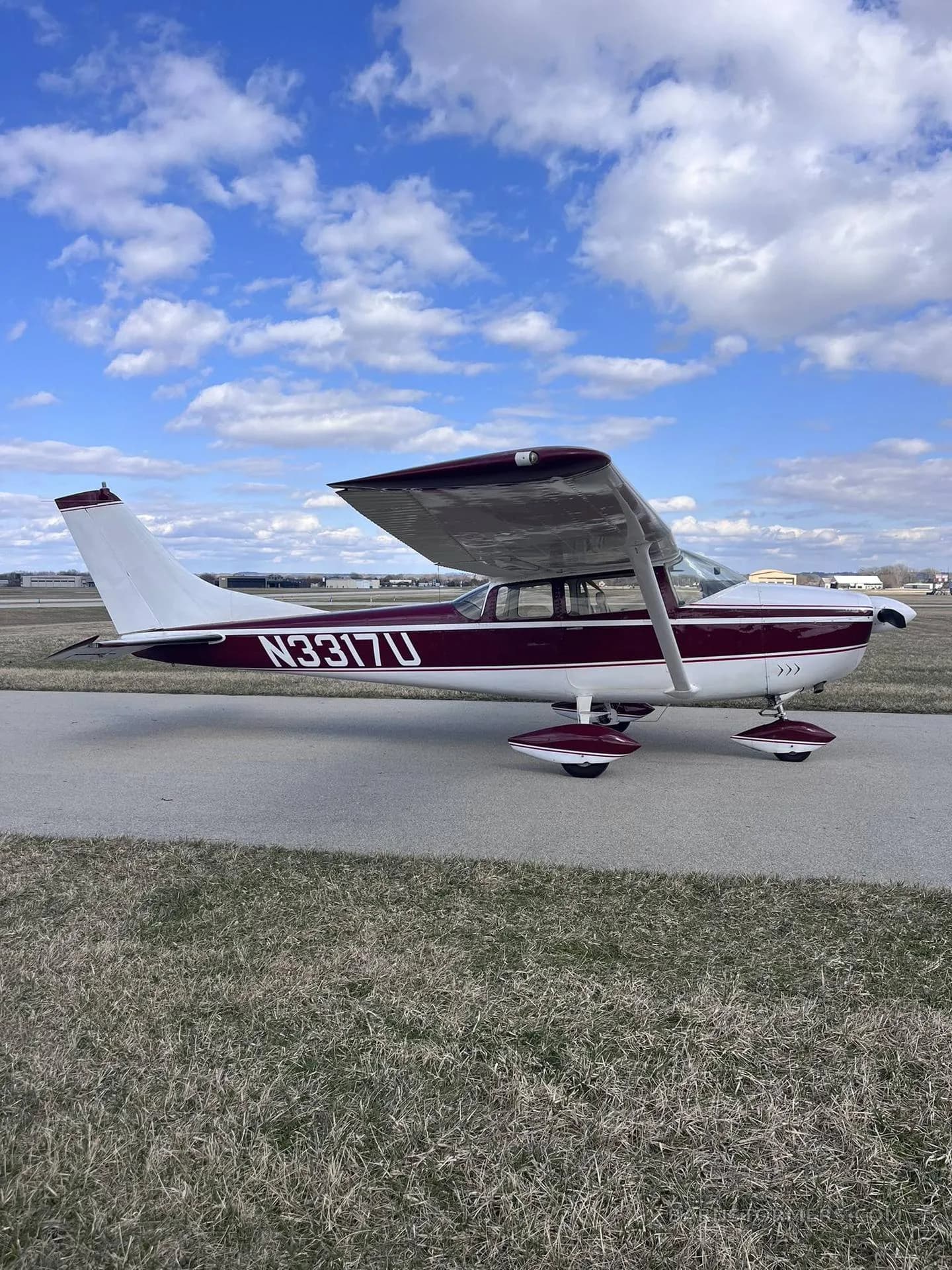 A maroon and white single-engine propeller aircraft (N3317U) viewed from the side, parked on an asphalt taxiway.