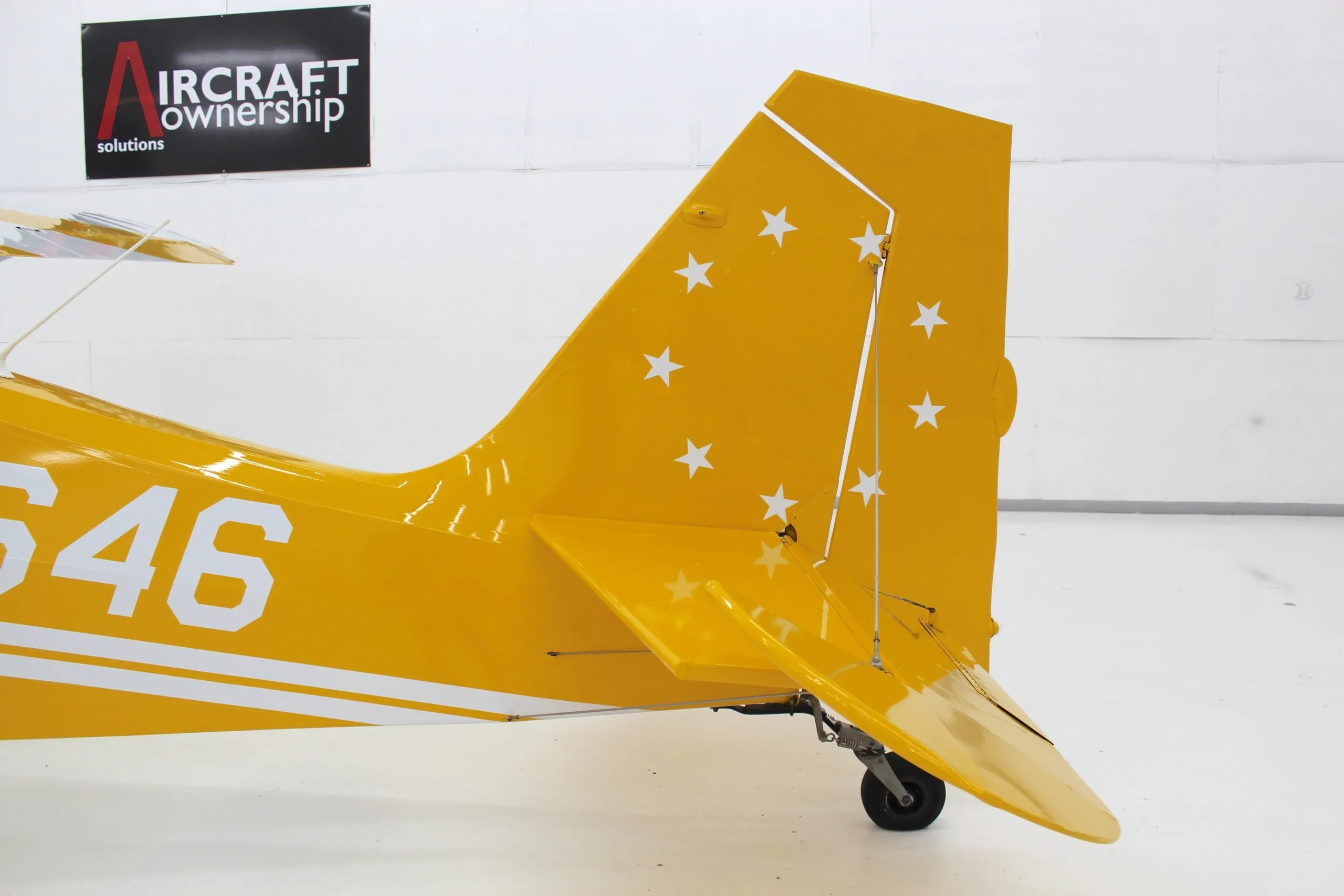 A close-up view of the yellow tail of N11646, adorned with white stars and the tailwheel.
