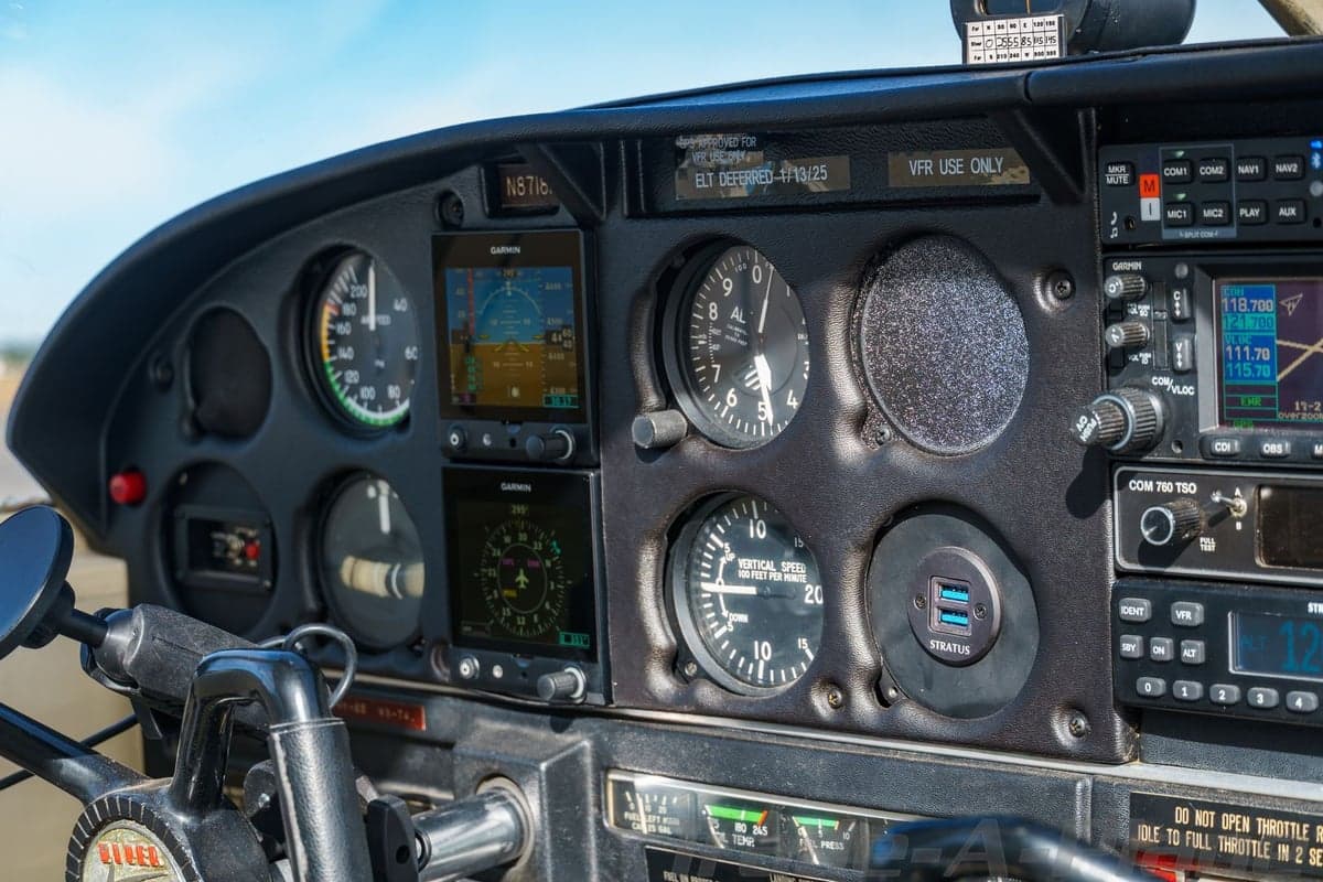 A close-up view of the instrument panel of the N8718N aircraft, featuring analog gauges and modern Garmin displays.