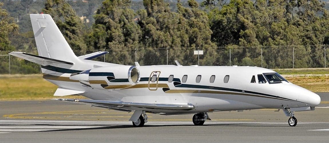 Side view of a white and gold Cessna Citation jet on the tarmac.