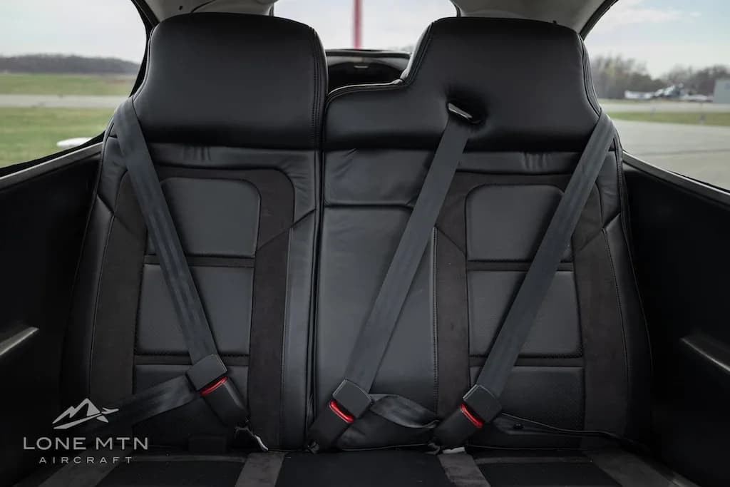 The black leather and suede rear seats of the aircraft cabin with seatbelts.