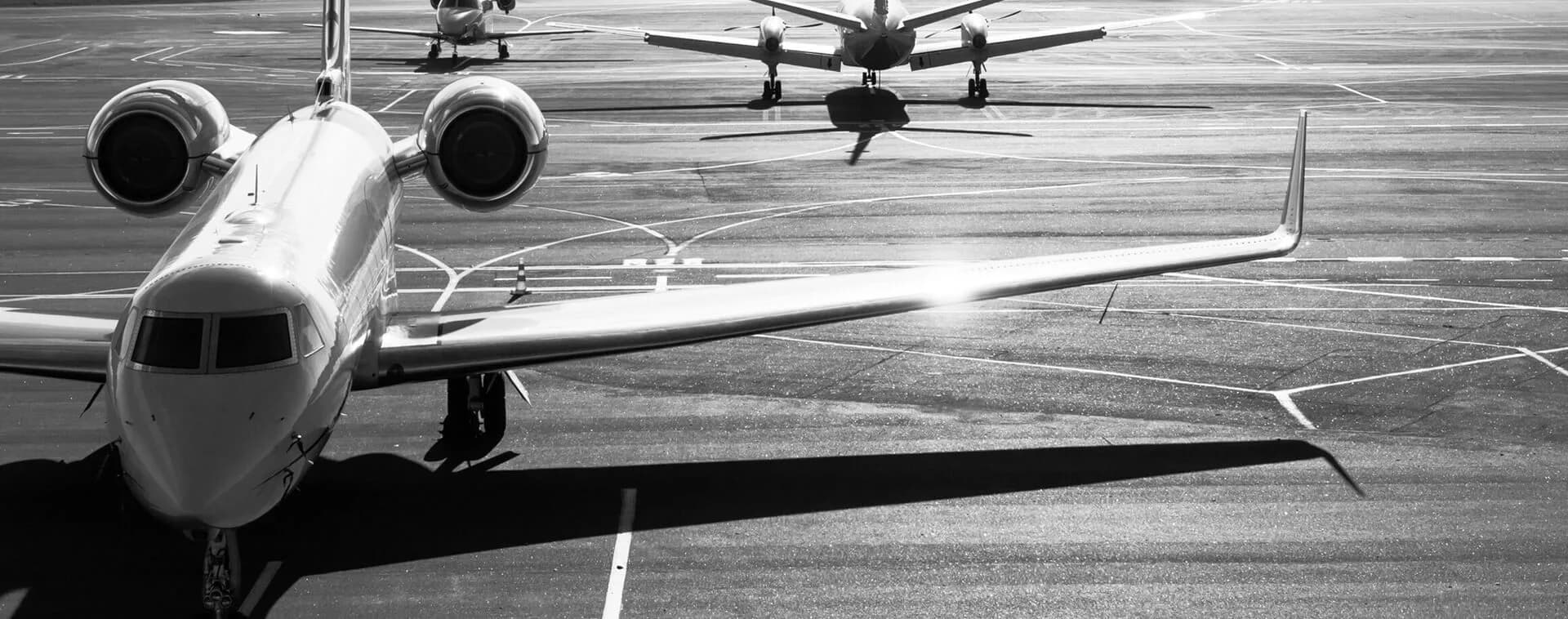 A black and white photo of multiple jet aircraft parked on an airport tarmac.