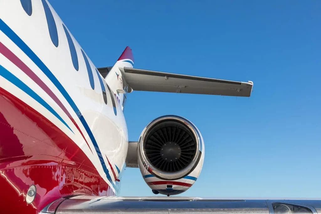 Close up of the tail and engine of a Falcon aircraft with red and white paint scheme.