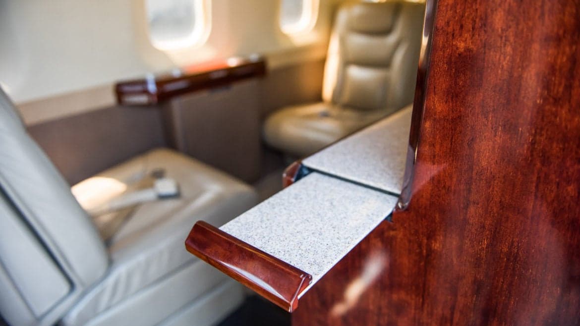 Interior of the aircraft showing a pull-out table and leather seats.