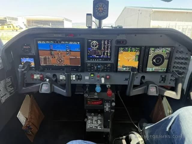 The modern glass cockpit of a Mooney aircraft, featuring multiple large digital displays and control yokes.