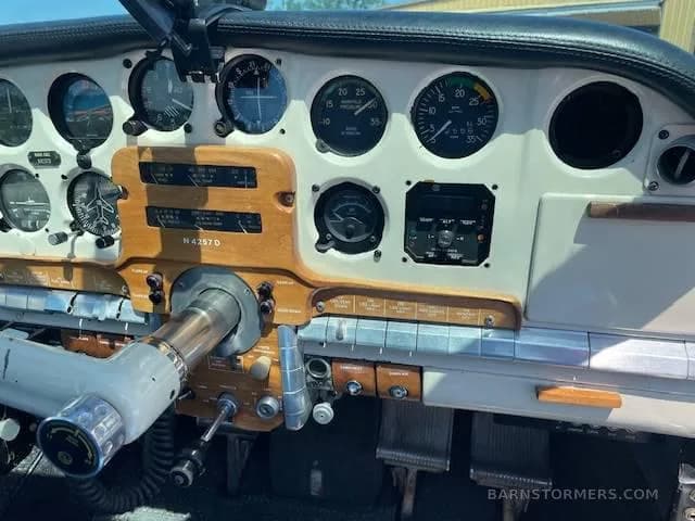 A close-up view of the aircraft's instrument panel, featuring analog gauges and a woodgrain trim.