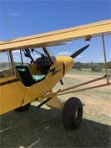 Close up of the cockpit and front of a yellow Cubcrafters aircraft.