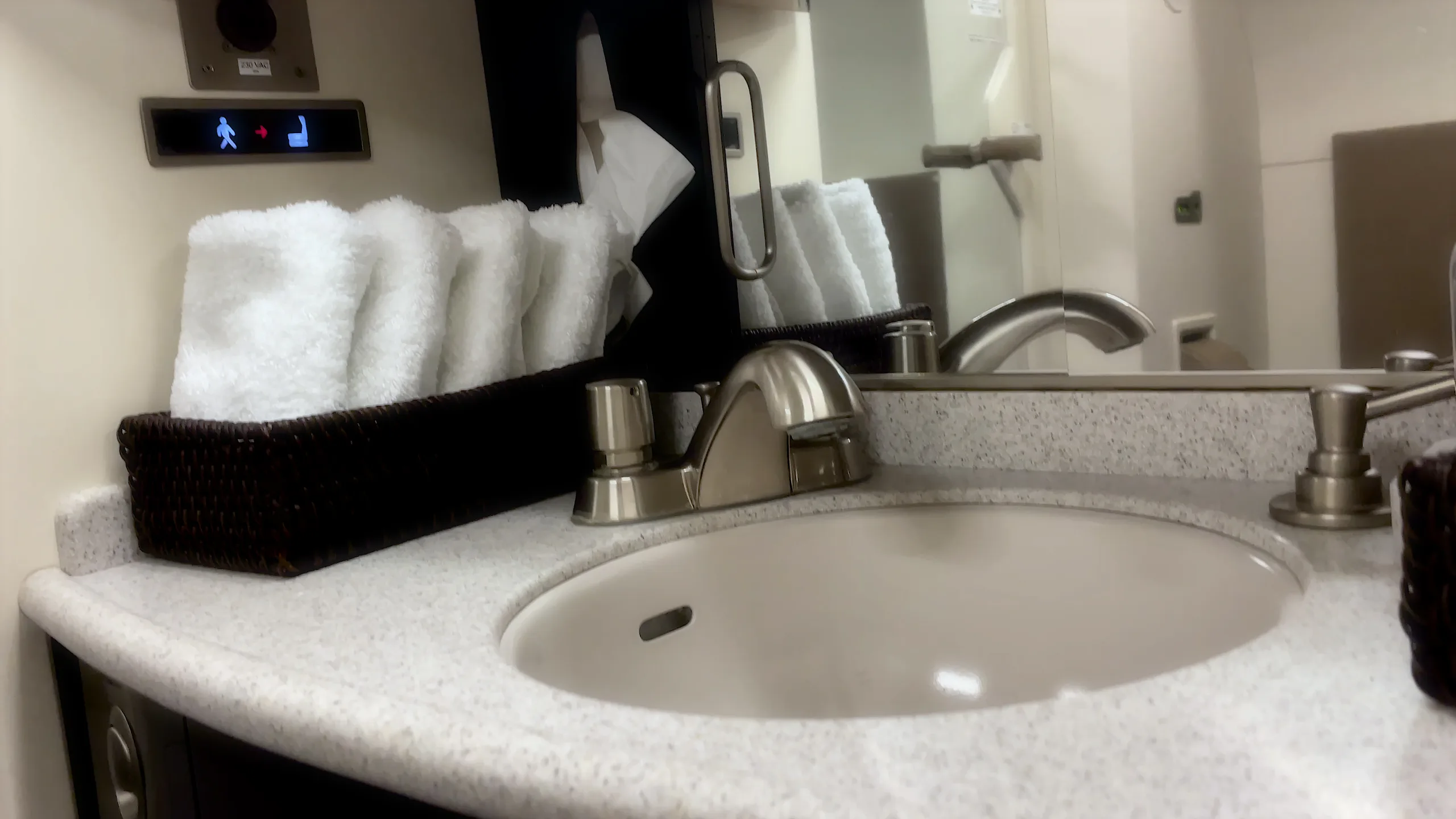 A lavatory sink with a faucet and neatly folded white towels inside a business jet.