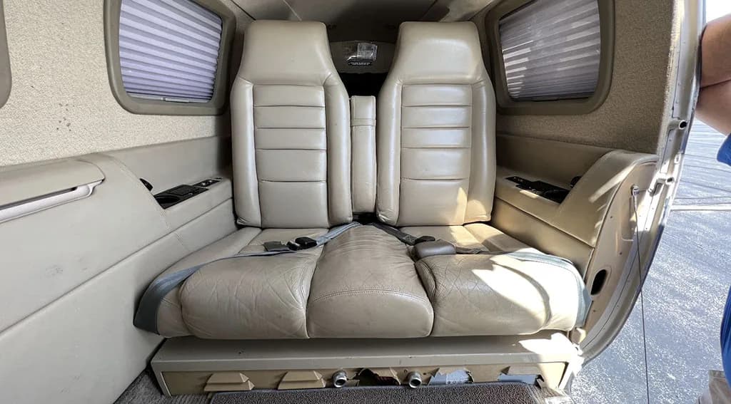 The light tan leather passenger seats in the cabin of a small aircraft.