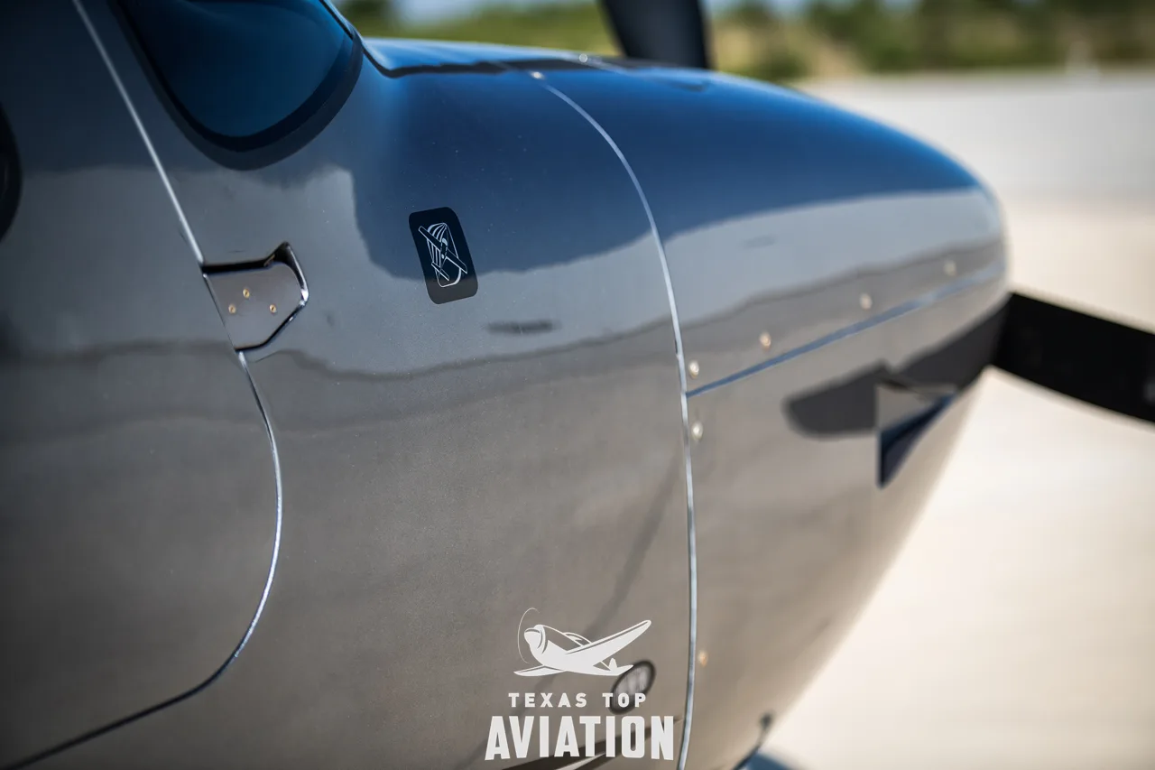 A close-up of the dark grey fuselage of the Cirrus SR22 aircraft near the propeller.