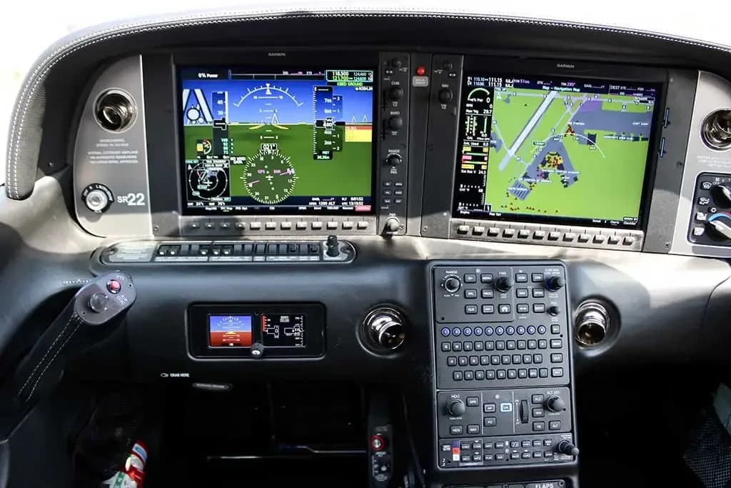 The modern glass cockpit of a Cirrus SR22 aircraft, featuring dual Garmin displays and a control panel.