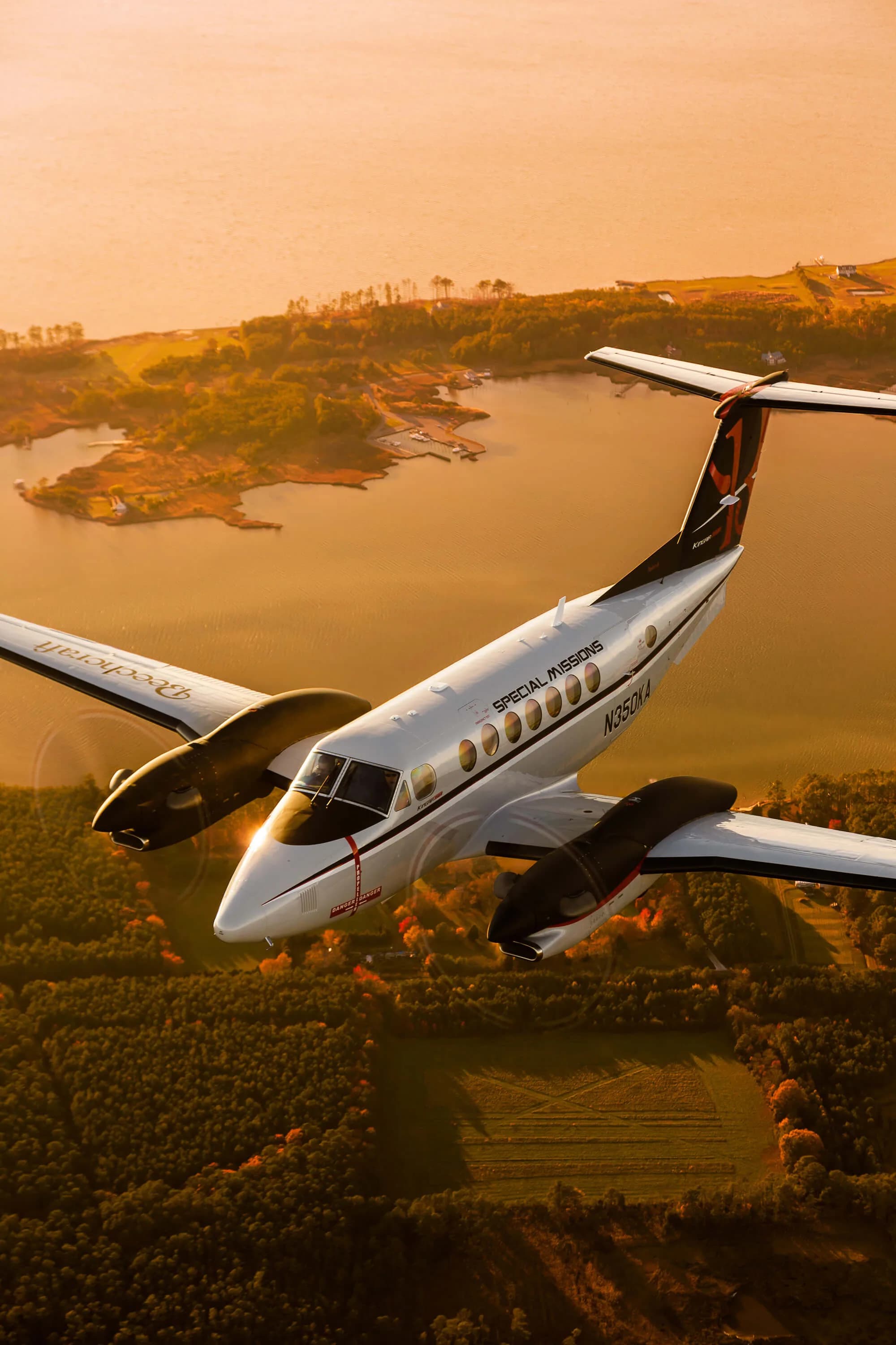 King Air 350 flying over a scenic landscape at sunset.