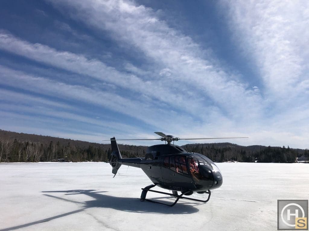An Airbus helicopter, registration C-FMTJ, is parked on a frozen lake.