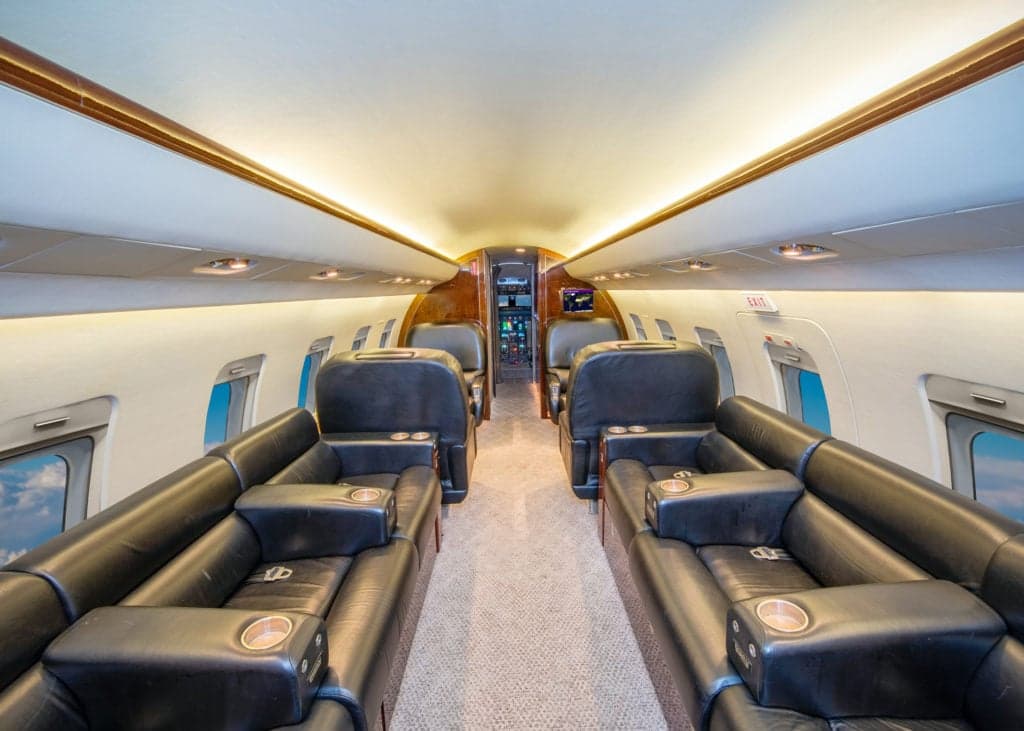 View of the Challenger aircraft interior with a galley and cockpit in the background.