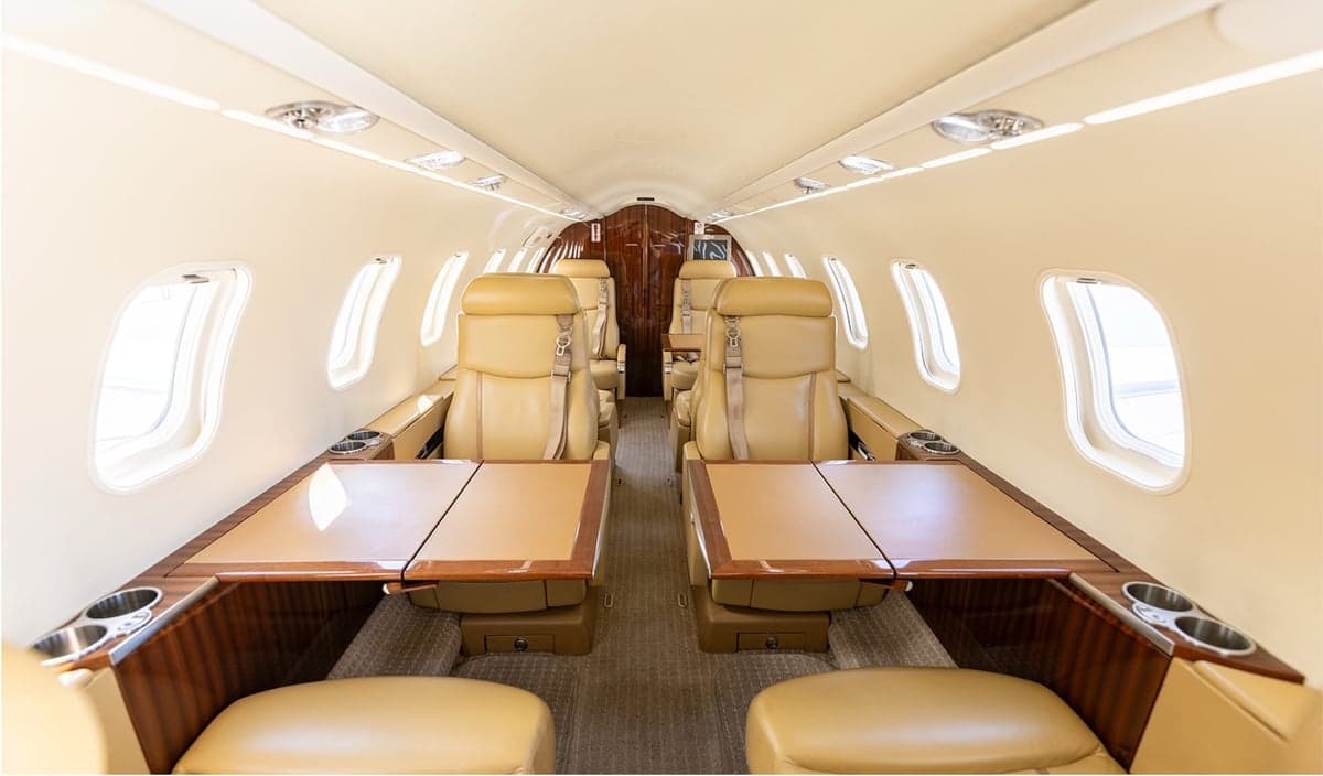 The interior cabin of an aircraft with tan leather seats and wood accents.