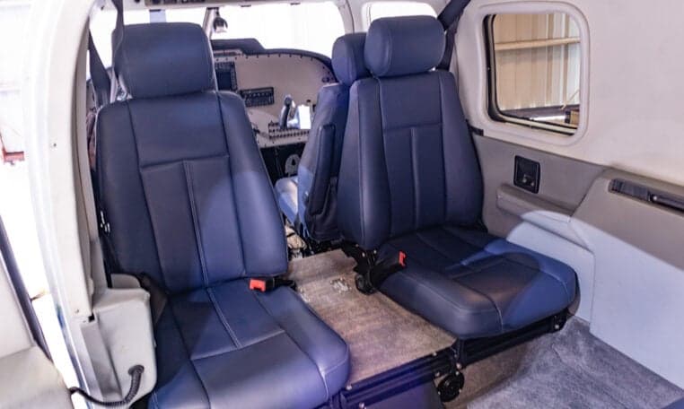 View of the aircraft cabin with blue leather seats and cockpit in the background.
