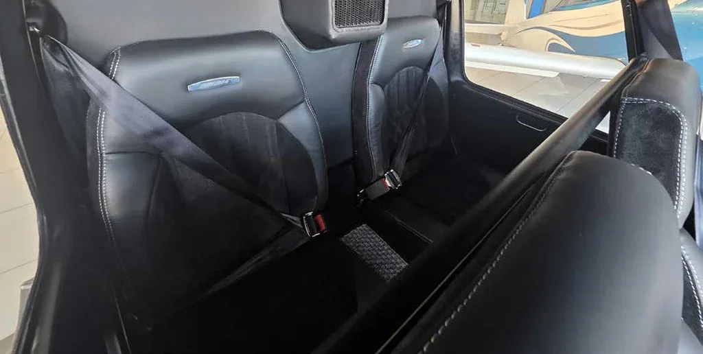 A close-up view of the black quilted leather and suede rear seats of a helicopter cabin.