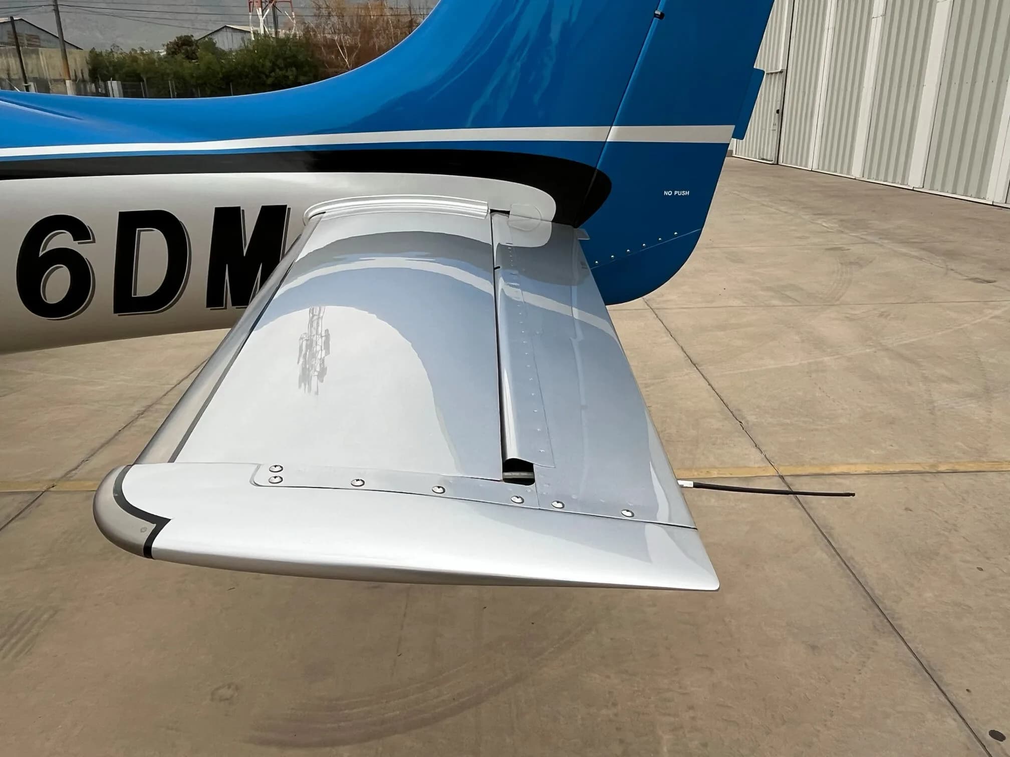 A close-up of the tail and horizontal stabilizer of the blue and silver Cirrus SR22 GTS aircraft.