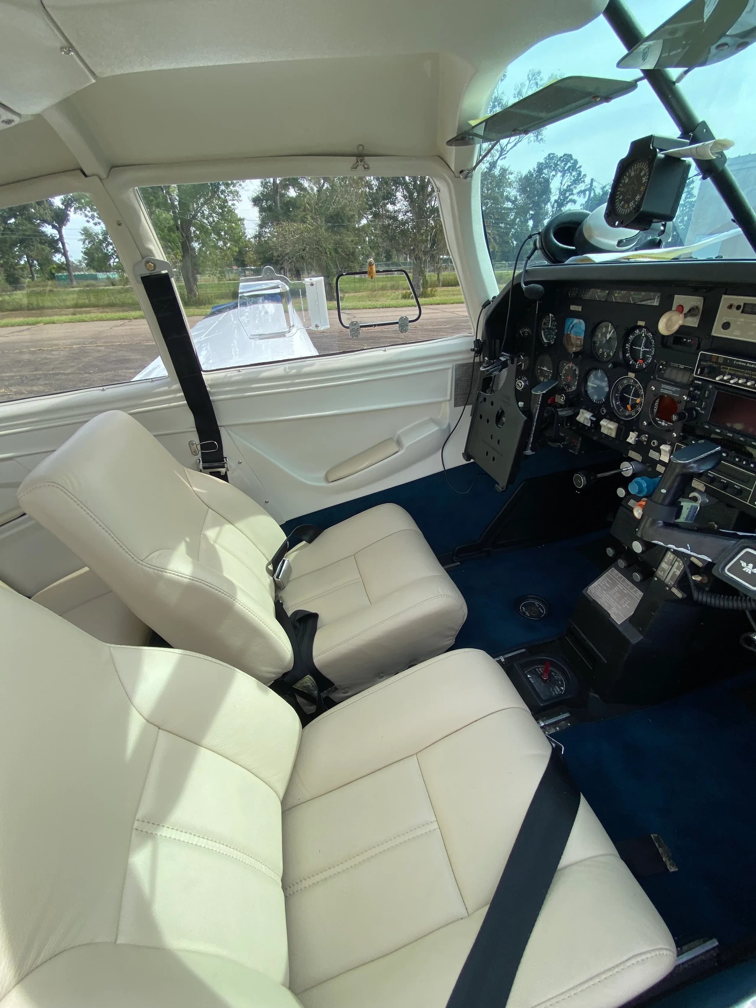 View from the cabin showing the cream-colored pilot seats and the aircraft's instrument panel.