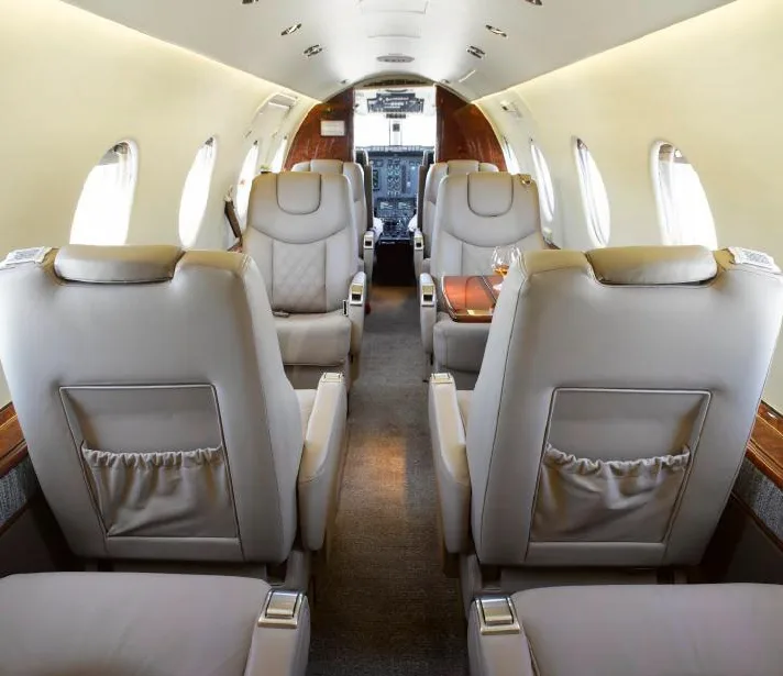 View of the Hawker 400XP cabin interior with leather seats and wood trim.