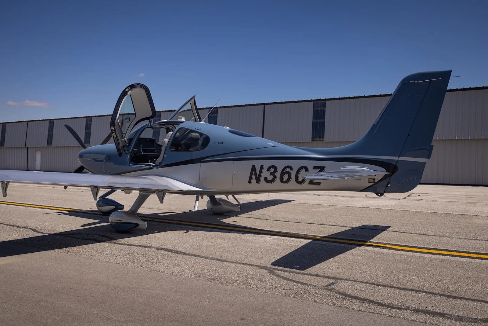 A Cirrus SR22T aircraft with open doors is parked on the tarmac.