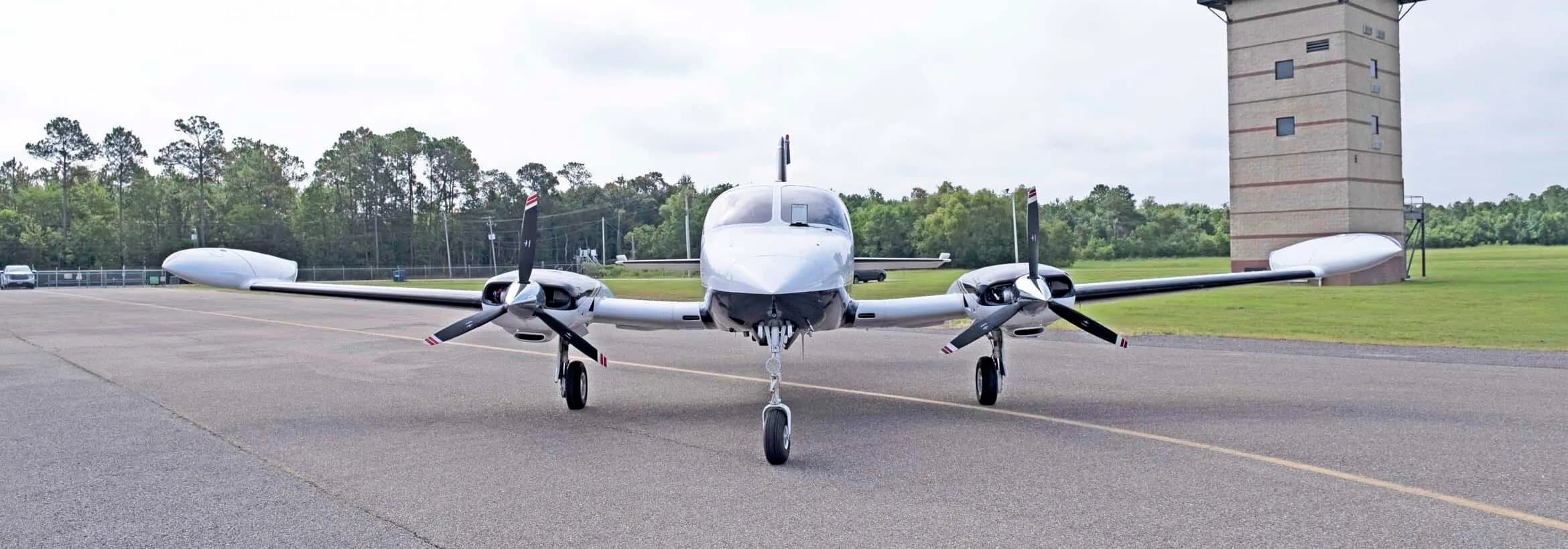 A head-on view of the white and dark blue Cessna 414 Chancellor, registration N991EM, parked on an airfield.