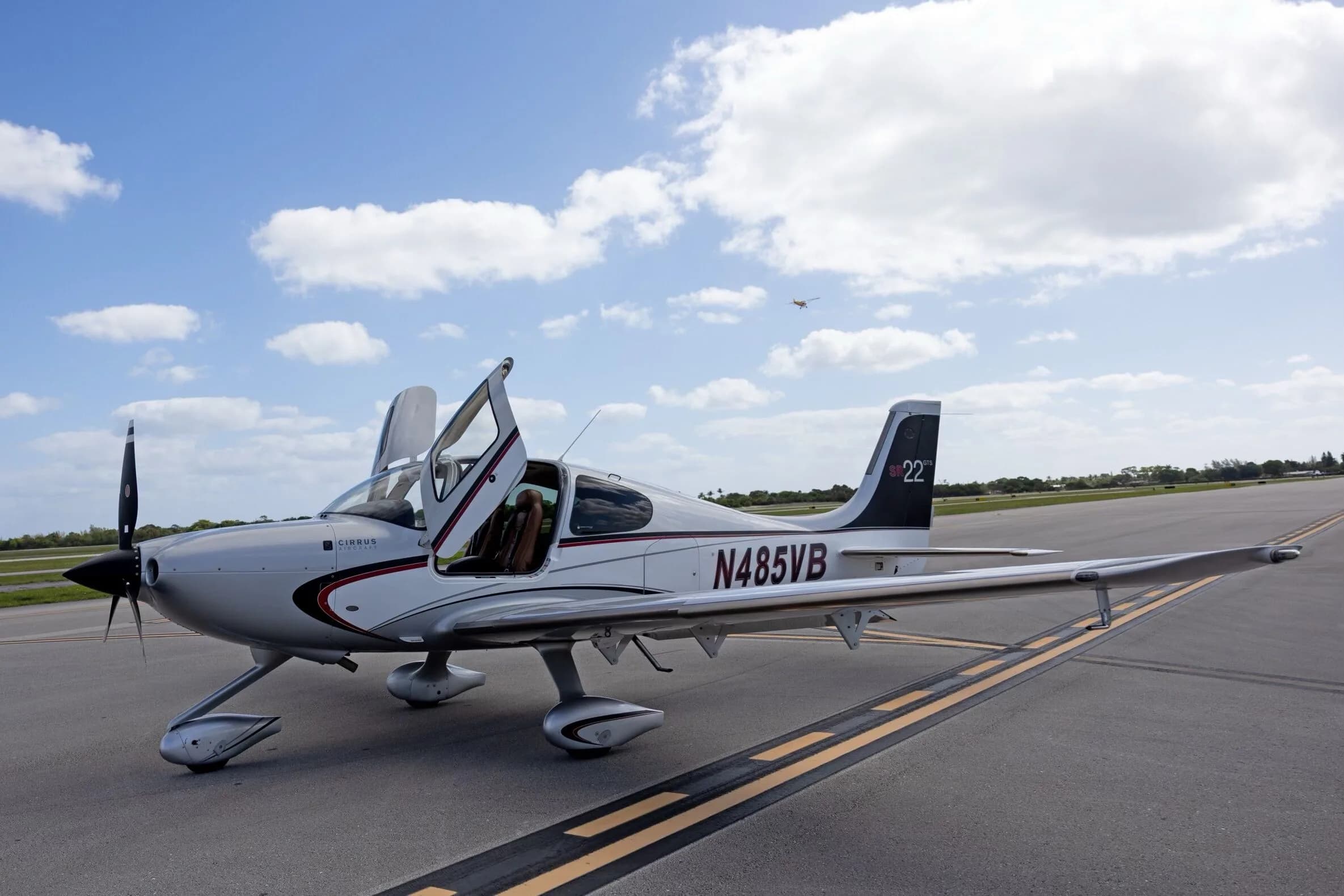A side view of the silver Cirrus SR22 GTS aircraft N485VB with its doors open, parked on an airfield.