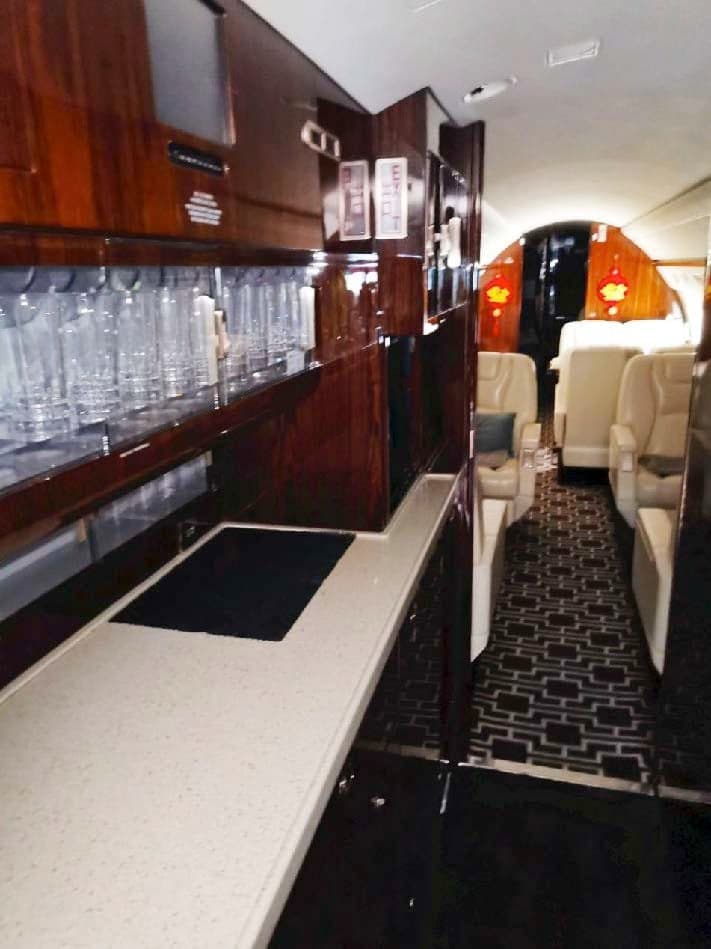 Galley area inside the aircraft cabin with dark wood cabinets and a white countertop.