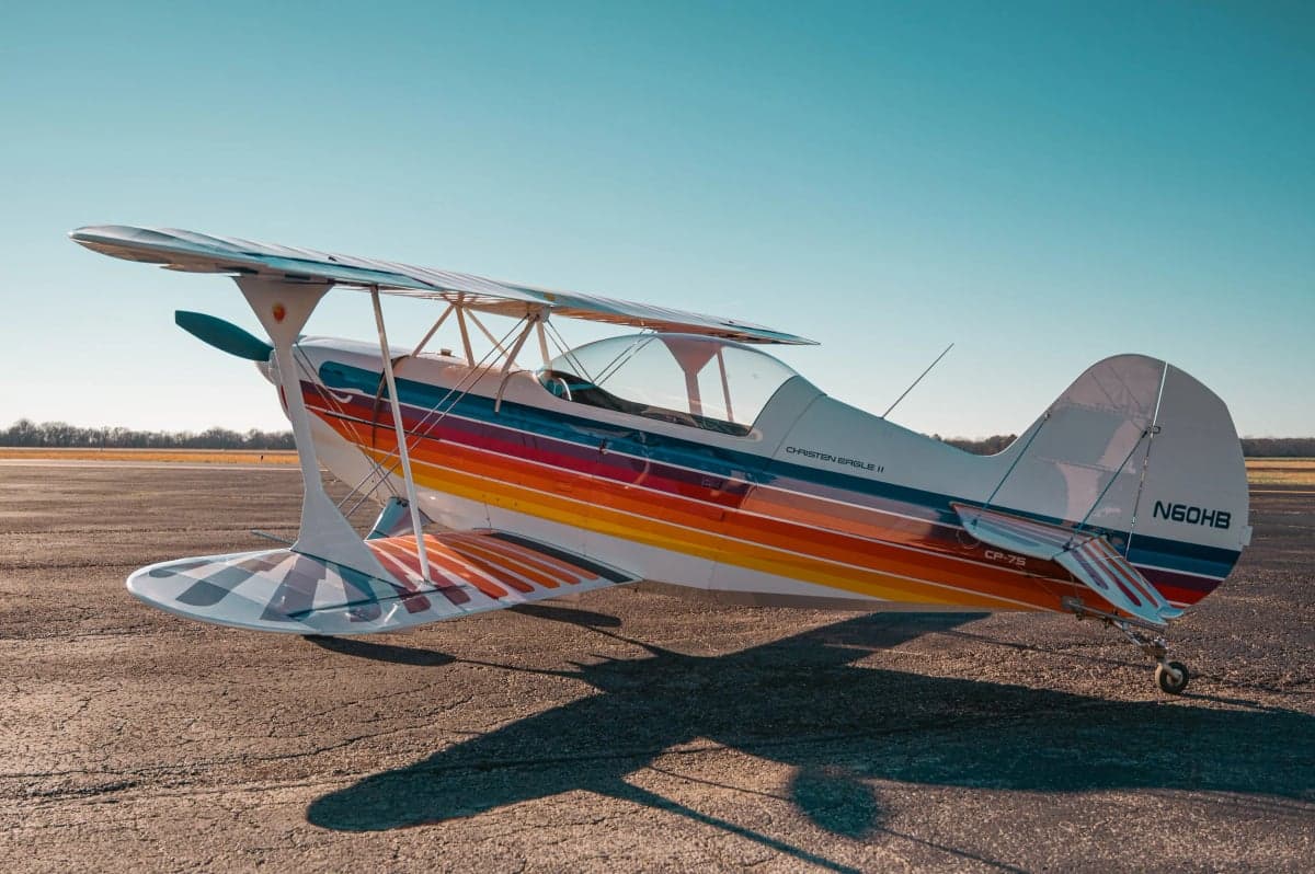 Christen Eagle II biplane with a colorful paint scheme parked on the tarmac.