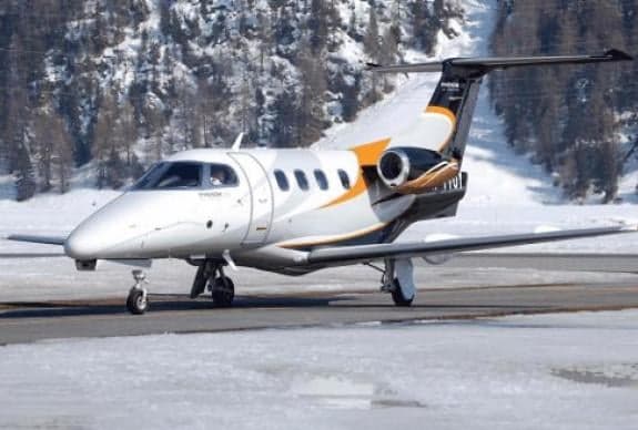 A Phenom 300 aircraft is shown on a snowy runway.