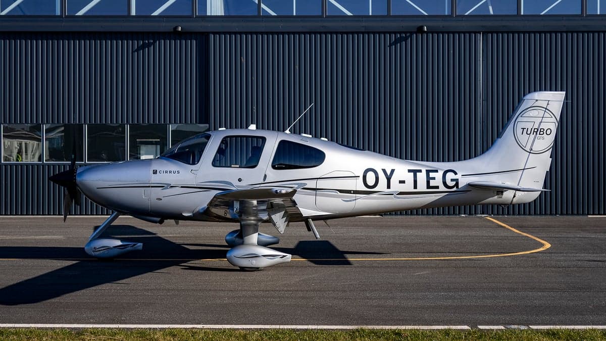 Side view of the silver Cirrus OY-TEG on the tarmac.