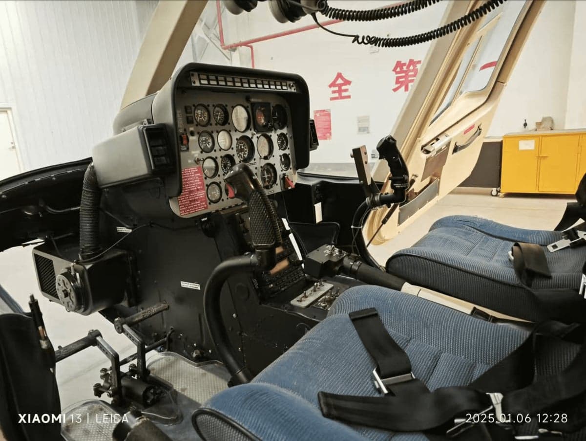 View of the helicopter cockpit with instrument panel and blue seats.