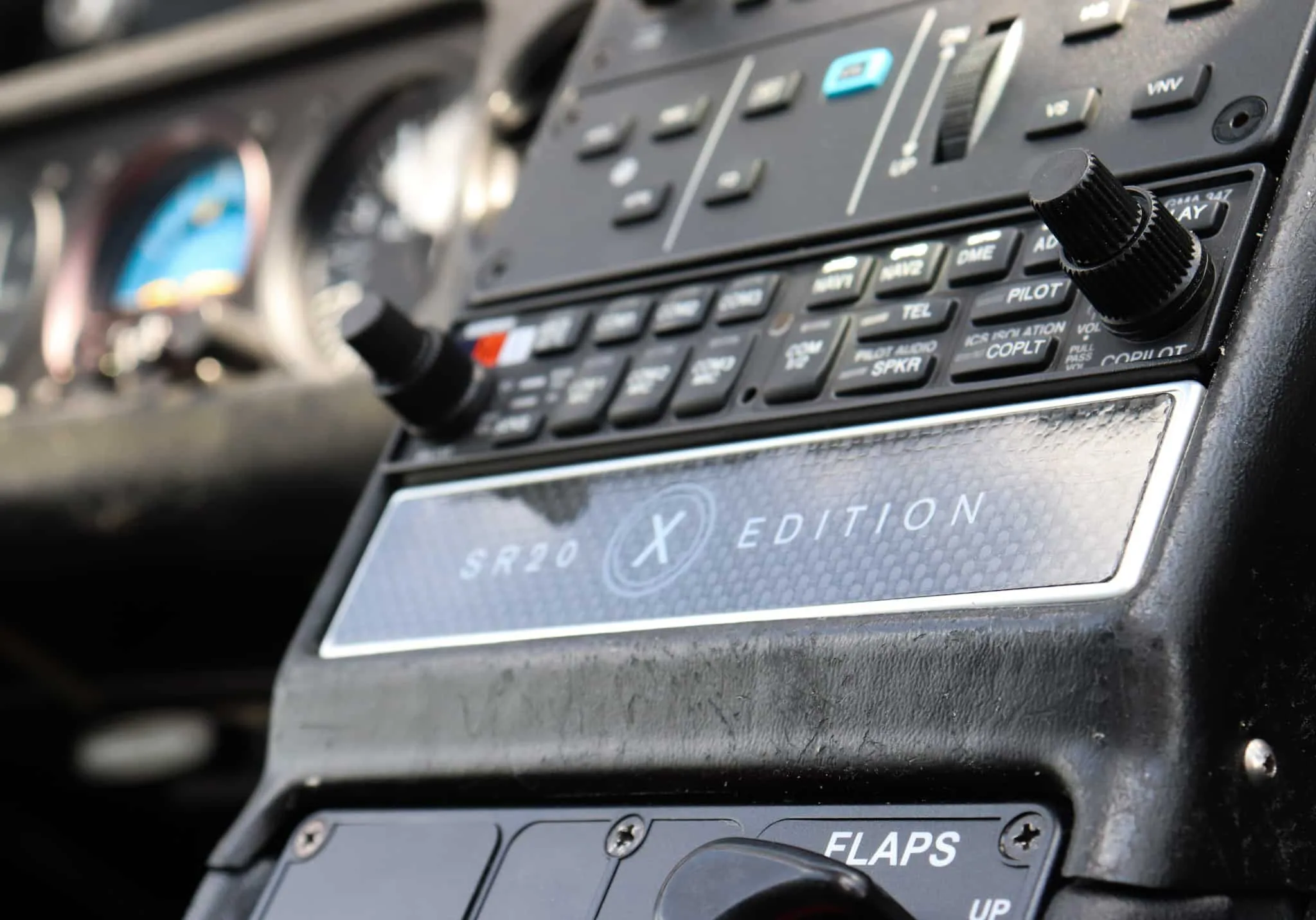 A close-up of the Cirrus SR20 X Edition center console with radio controls and flap switch.