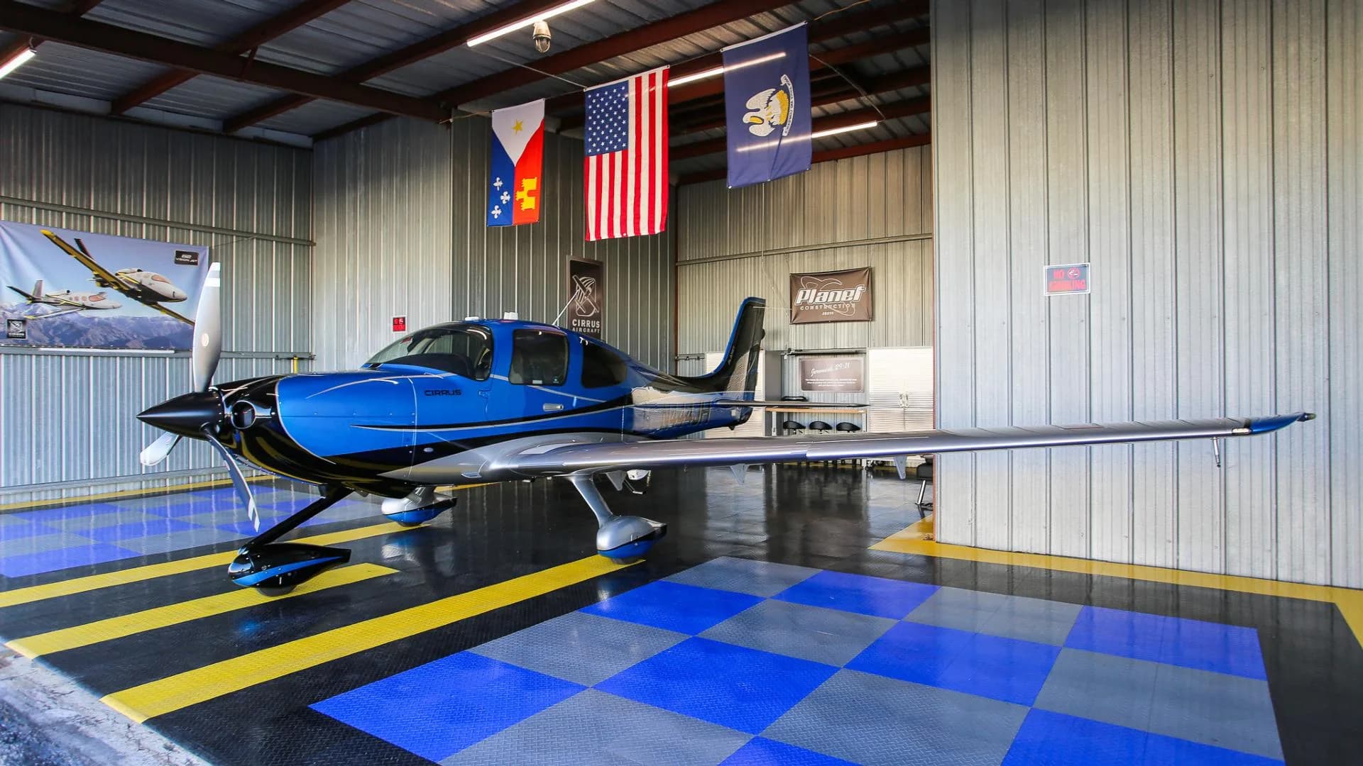A blue and silver Cirrus SR22 aircraft with registration N444JH parked inside a hangar.