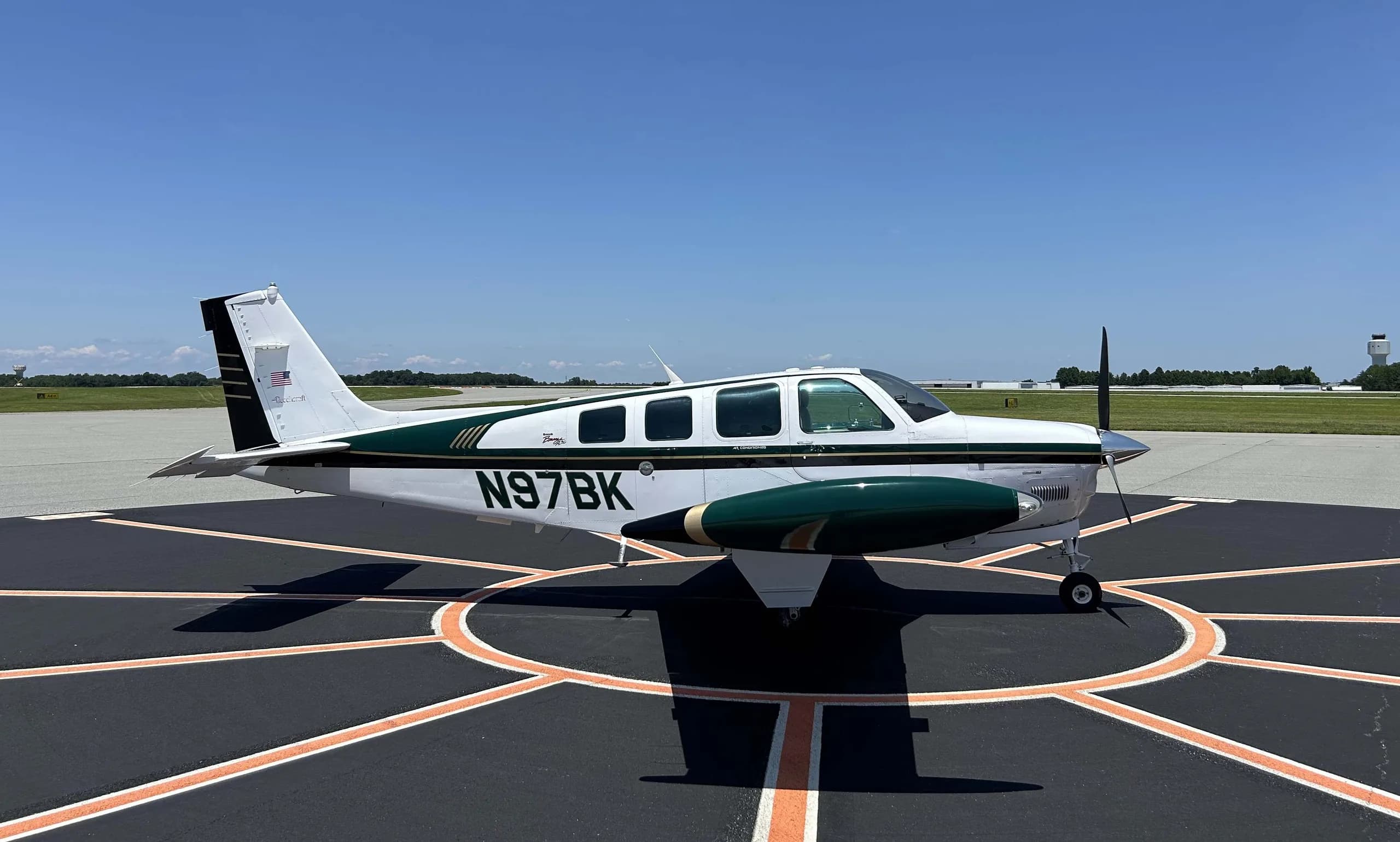 Beechcraft Bonanza N97BK with white and green paint scheme on a tarmac.