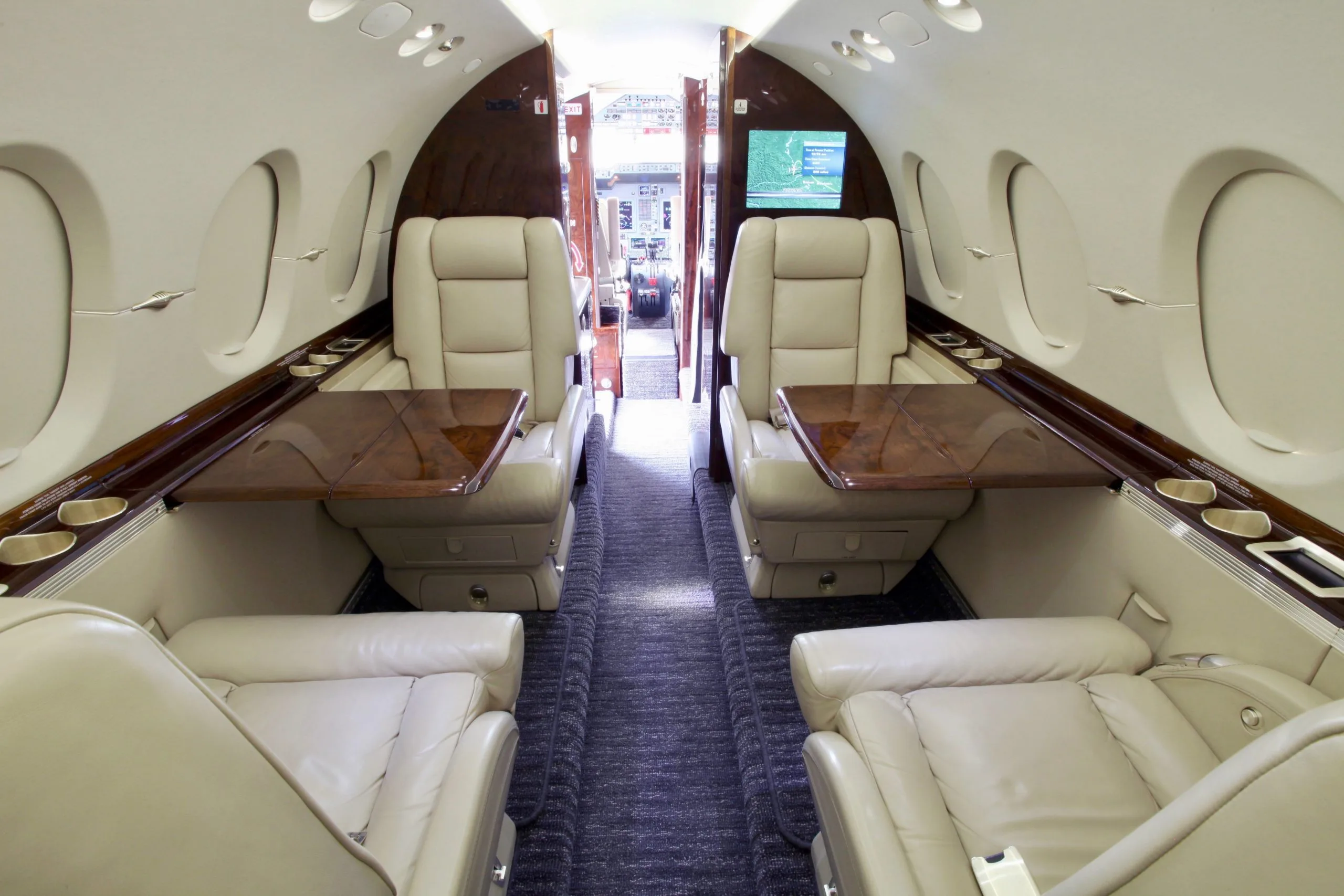The interior of a Hawker 400XP aircraft with leather seats and wooden tables.