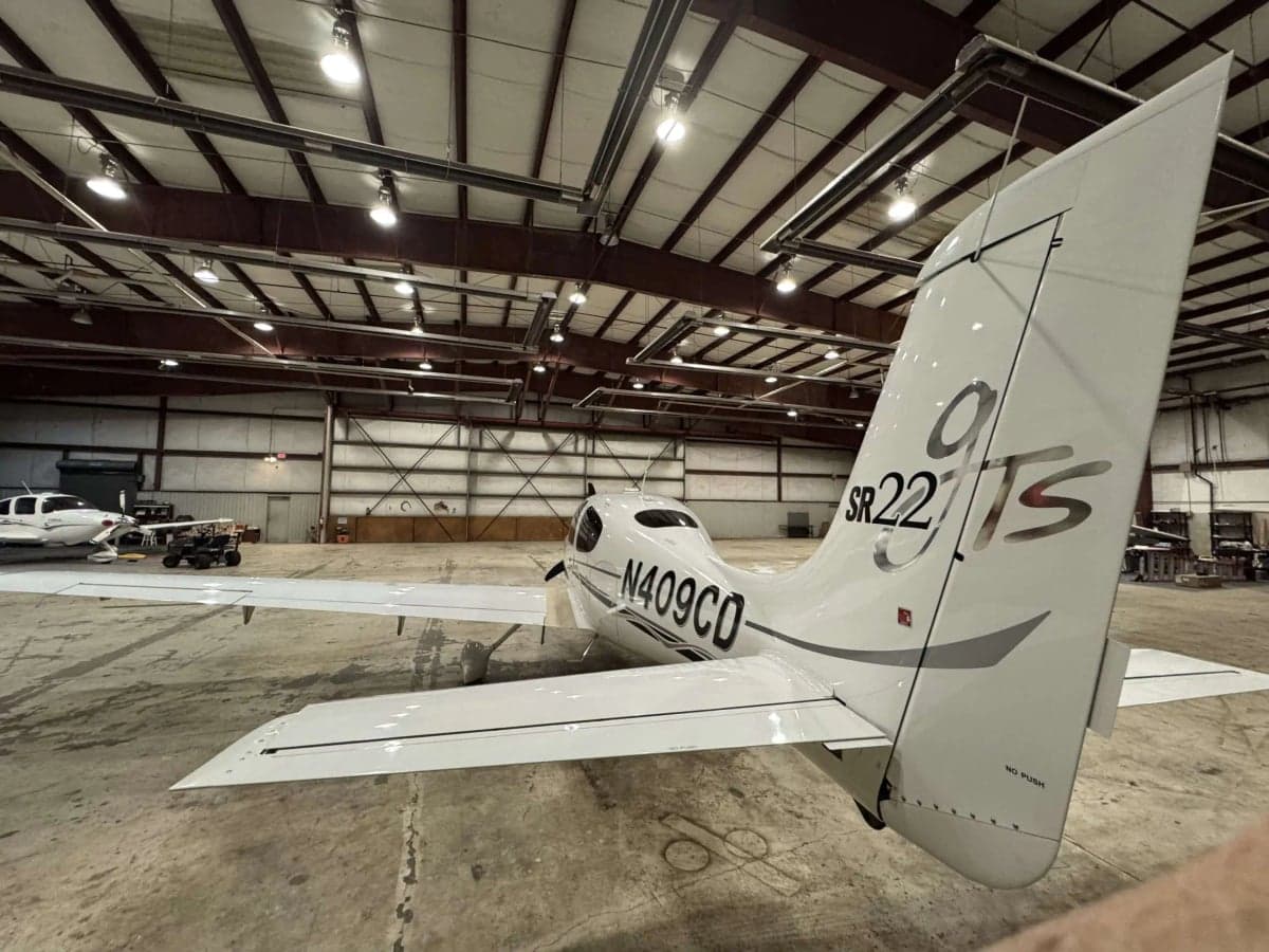 Rear view of a Cirrus SR22T in a hangar, showing the tail and registration number N409CD.