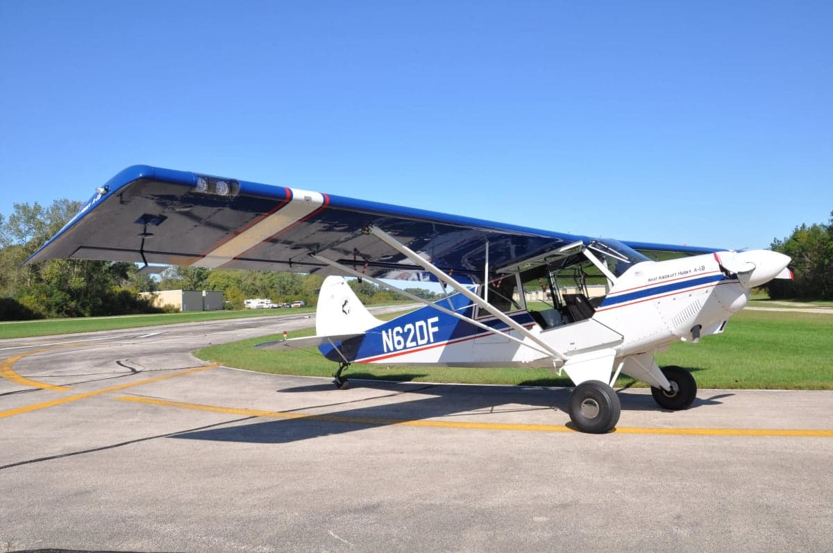 A white and blue CubCrafters Carbon Cub EX-3 on the tarmac.