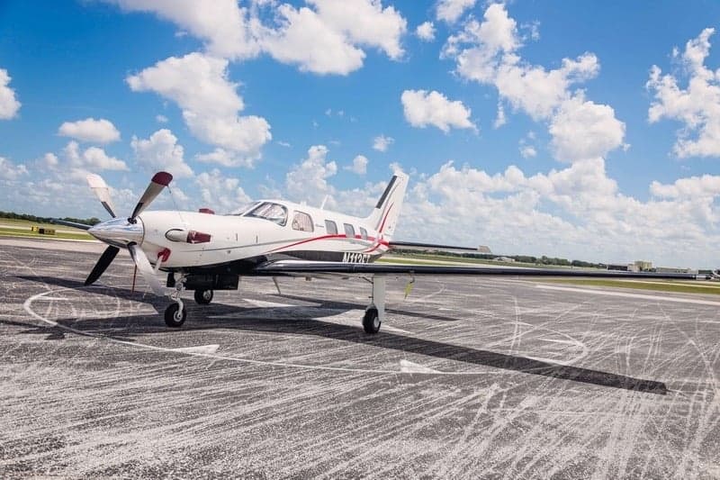 Piper Meridian aircraft parked on the tarmac under a partly cloudy sky.