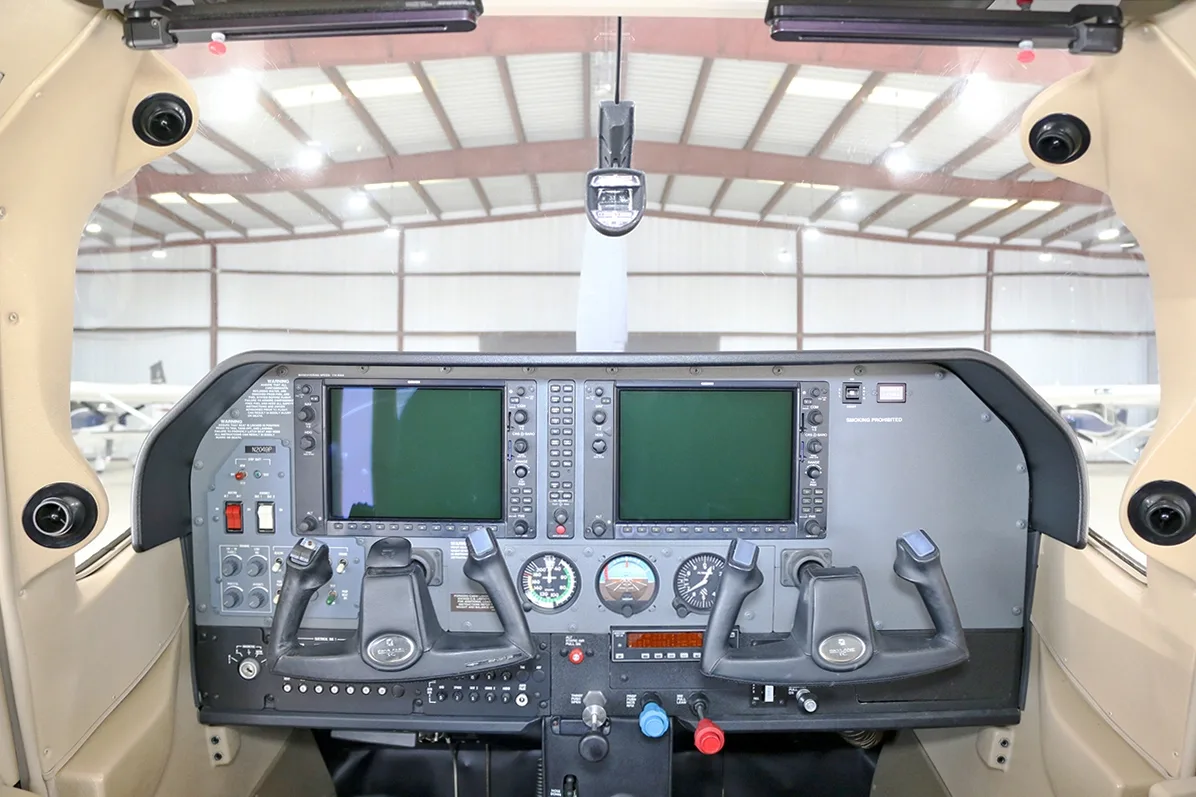 View of the aircraft cockpit with dual display screens and control yokes.