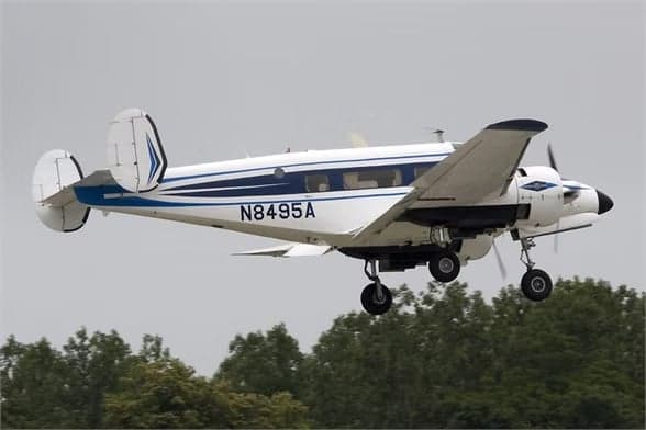 Beechcraft Model 18 with registration N8495A on the runway with smoke.